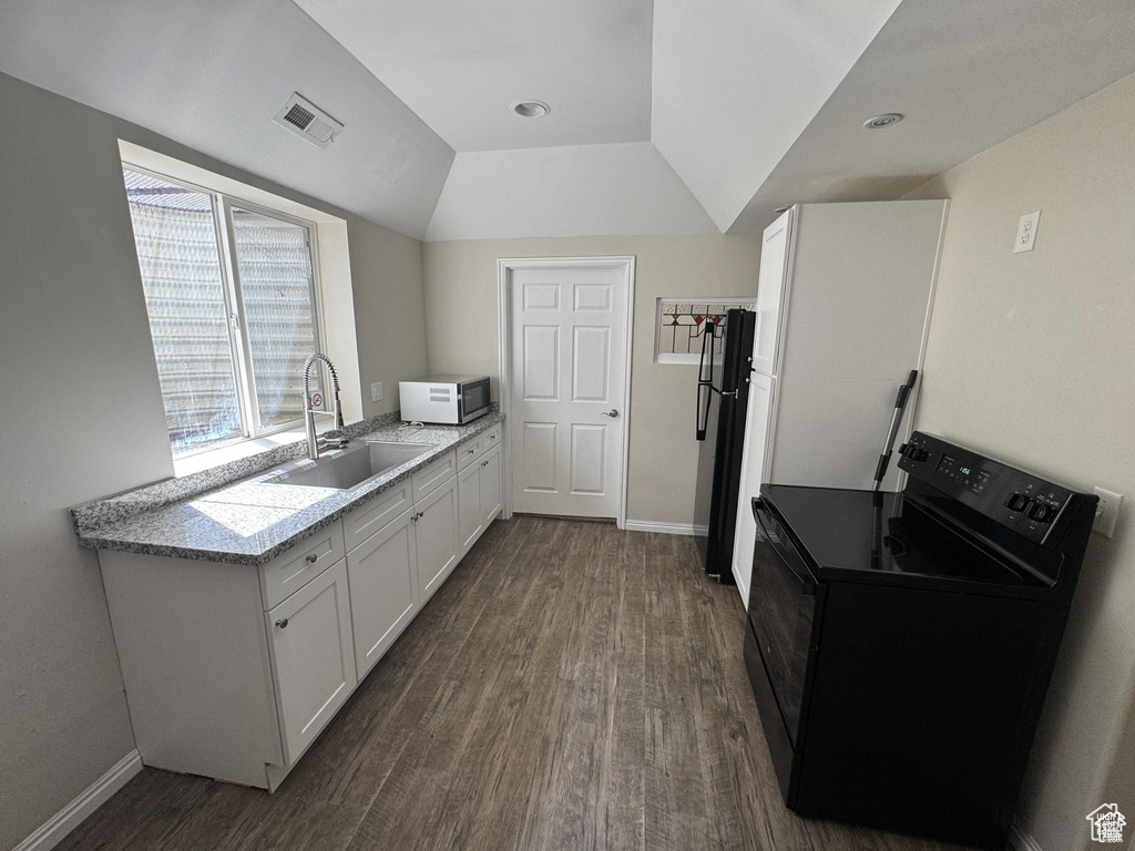 Kitchen with black electric range, a sink, dark wood finished floors, white cabinetry, and light countertops