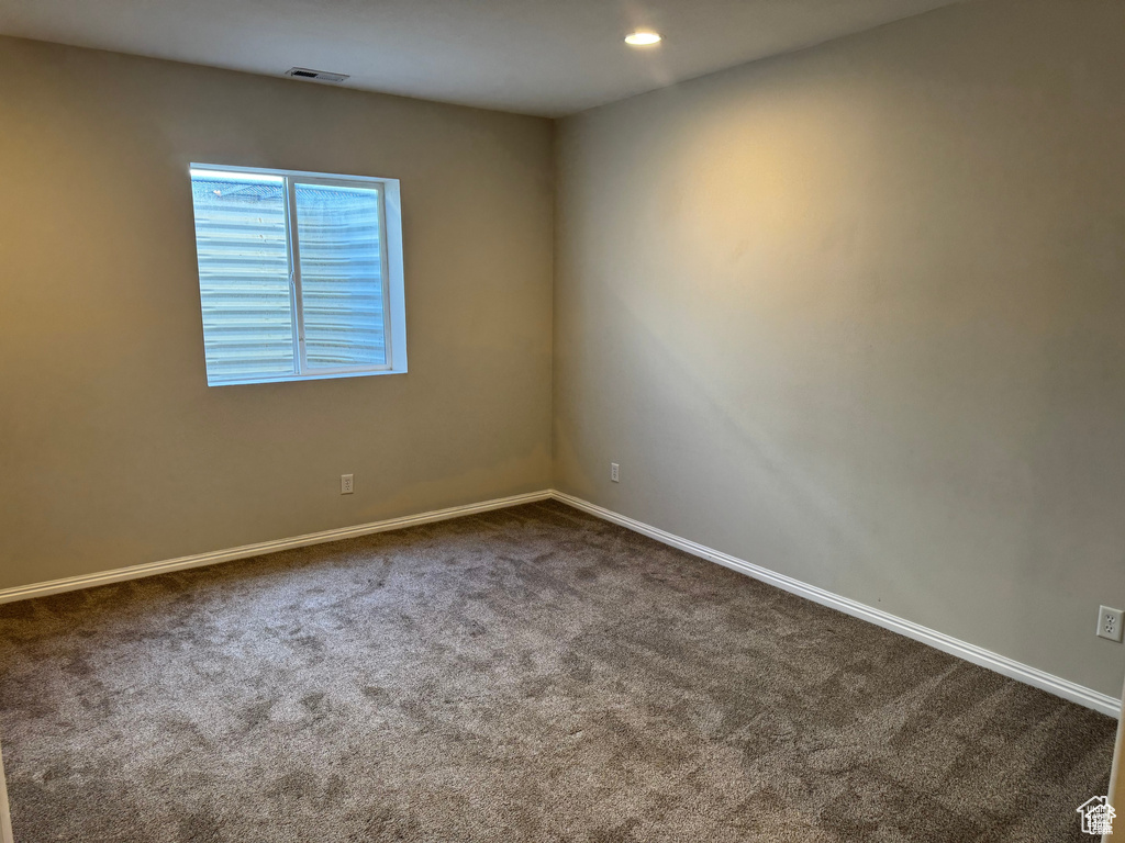 Spare room with dark carpet, baseboards, and recessed lighting