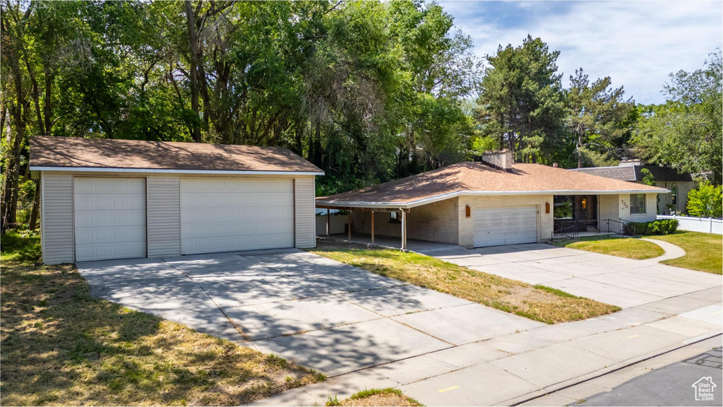Ranch-style home with a chimney, a detached garage, brick siding, an outdoor structure, and a front yard