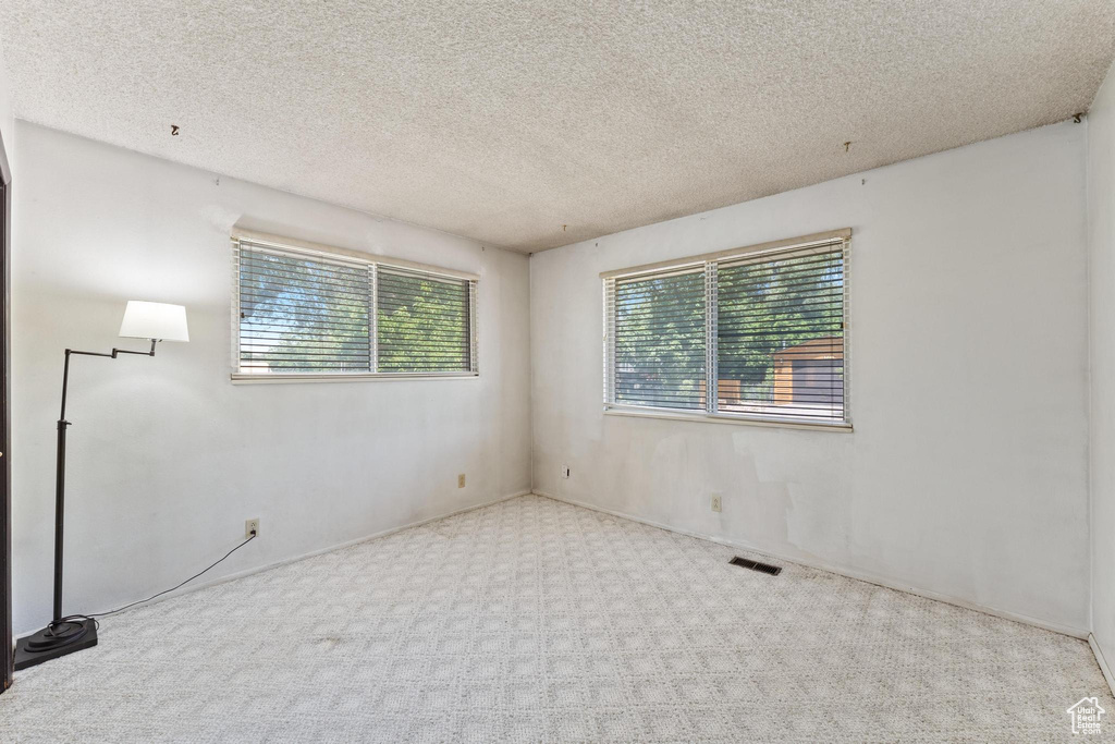 Carpeted empty room with a textured ceiling