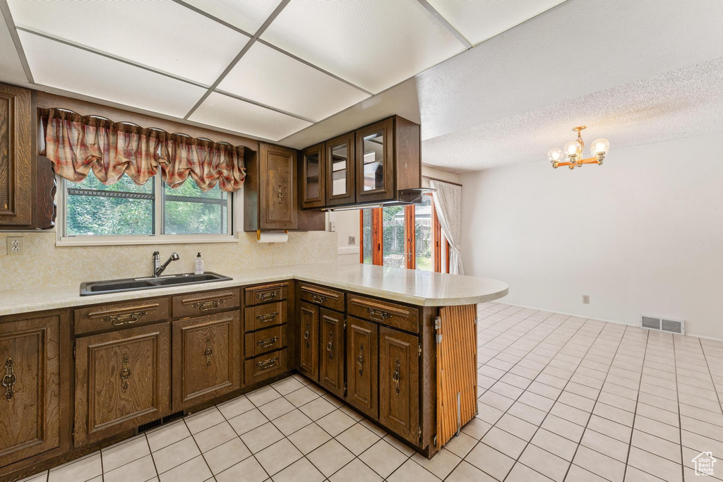 Kitchen featuring a sink, a peninsula, light countertops, and decorative backsplash