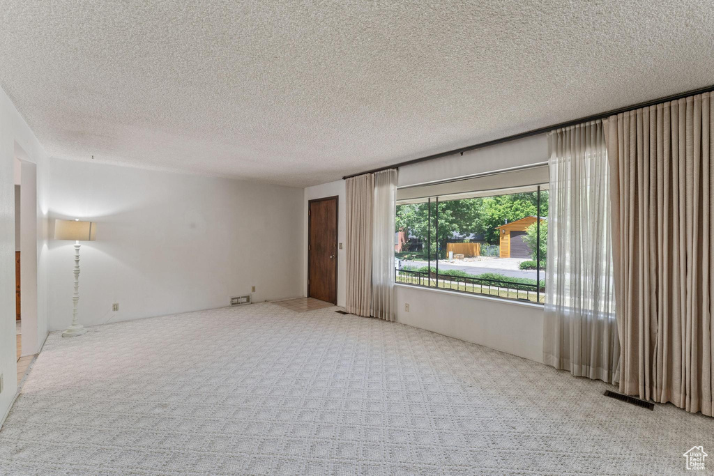 Carpeted empty room featuring a textured ceiling