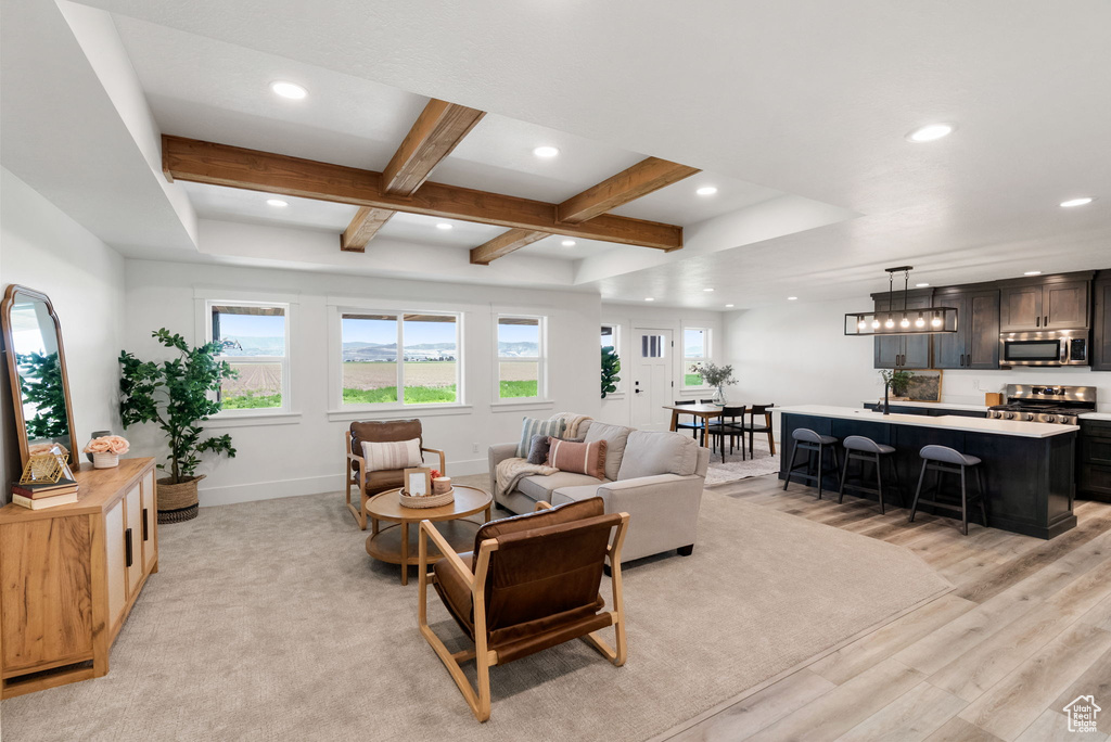 Living area featuring healthy amount of natural light, coffered ceiling, light wood-style flooring, recessed lighting, and beamed ceiling