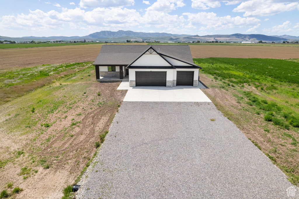 Ranch-style house with driveway, a garage, a view of rural / pastoral area, and a mountain view