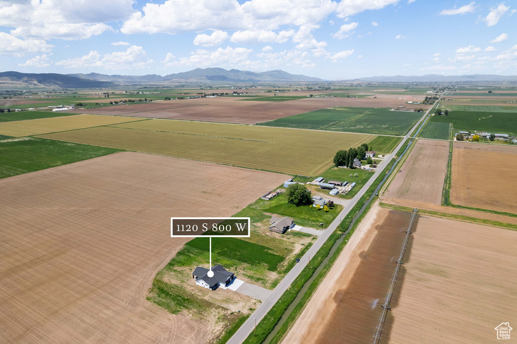 Aerial view of property and surrounding area featuring rural landscape, a mountainous background, and extensive farmland