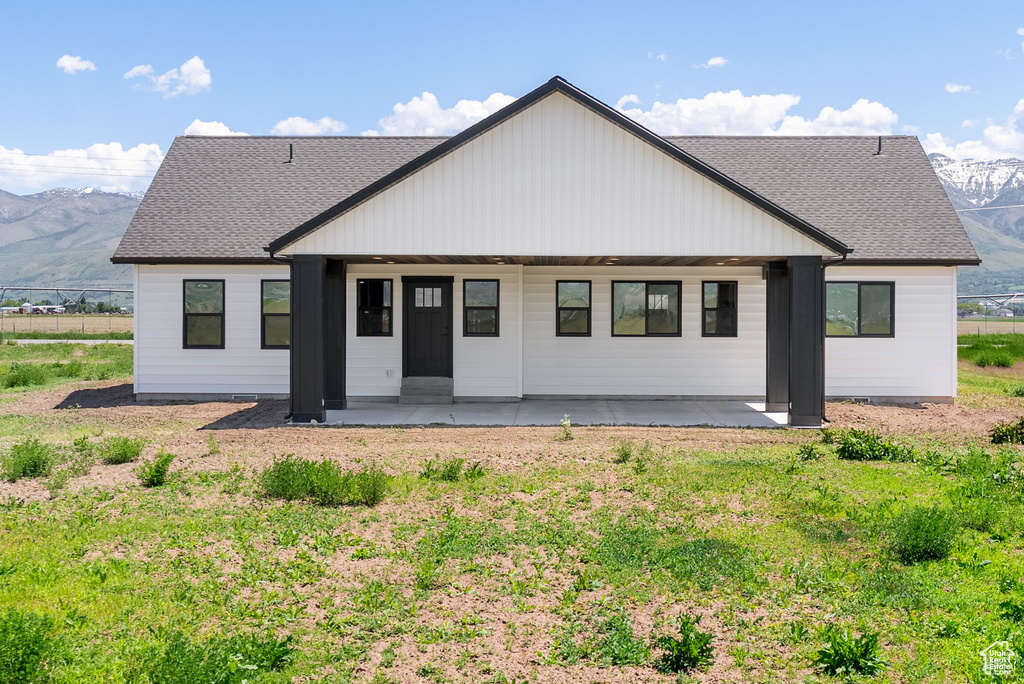 Rear view of house with a mountain view, a shingled roof, and a patio area