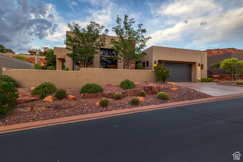 Southwest-style home featuring a fenced front yard, concrete driveway, stucco siding, and an attached garage