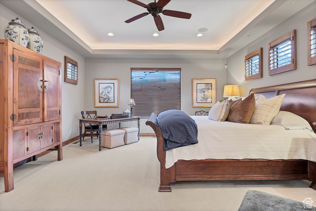 Carpeted bedroom featuring a tray ceiling, ceiling fan, baseboards, and recessed lighting