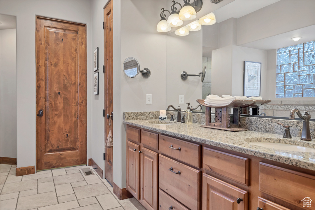 Bathroom featuring baseboards, double vanity, a sink, and stone tile floors
