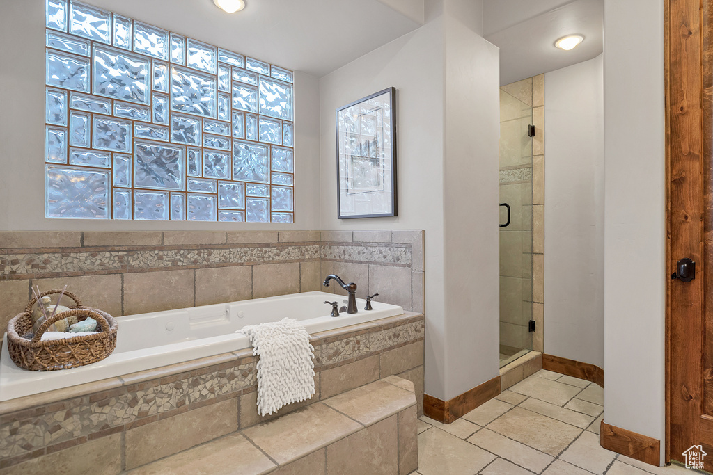 Bathroom featuring tile patterned flooring, a shower stall, a bath, and baseboards