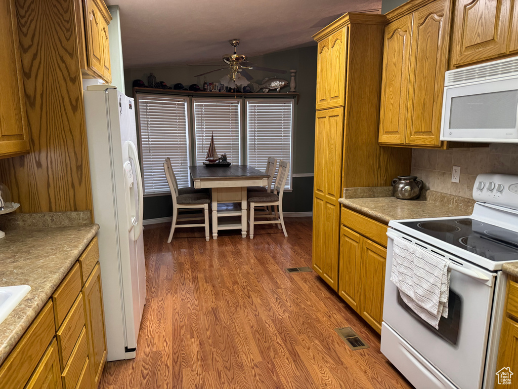 Kitchen featuring white appliances, a ceiling fan, wood finished floors, and light countertops
