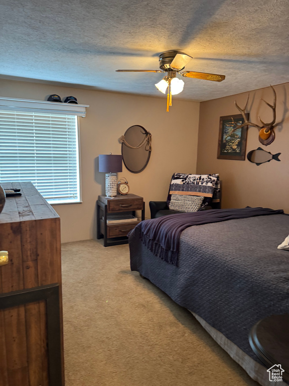 Bedroom with light carpet, a textured ceiling, and ceiling fan