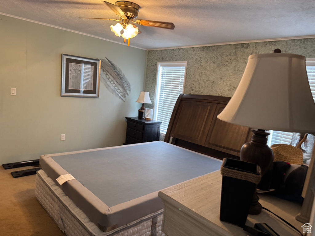 Bedroom with ornamental molding, ceiling fan, wallpapered walls, and carpet floors