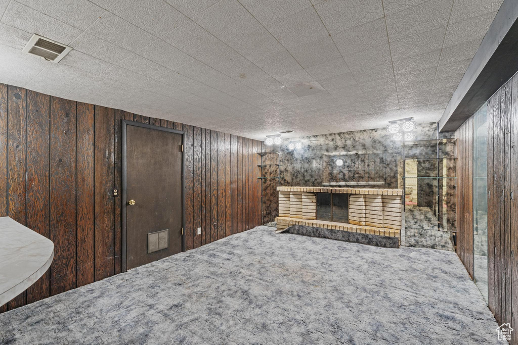 Unfurnished living room featuring wooden walls, carpet, and a fireplace