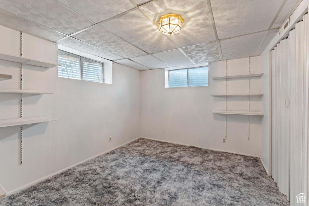 Below grade area with carpet, healthy amount of natural light, baseboards, and a paneled ceiling