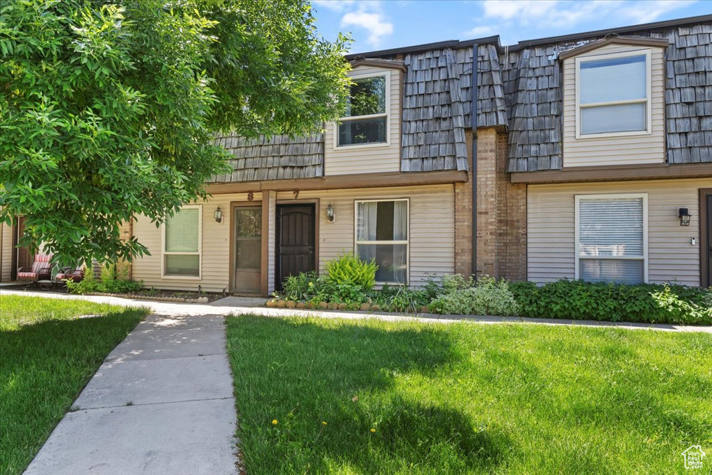 Townhome / multi-family property with mansard roof and a front yard