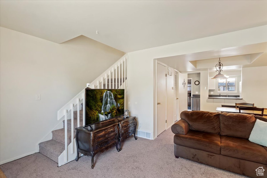 Living room with stairway, light carpet, and baseboards