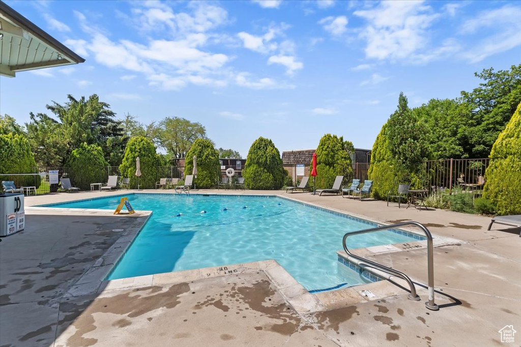 Community pool with a patio and view of scattered trees