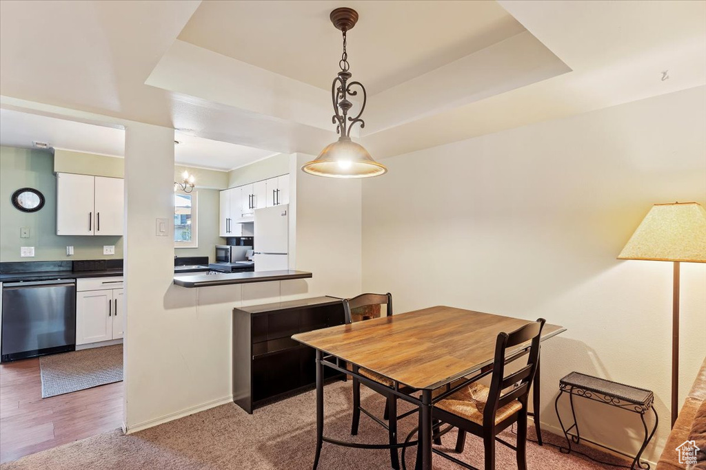 Dining space featuring a tray ceiling, baseboards, and a chandelier