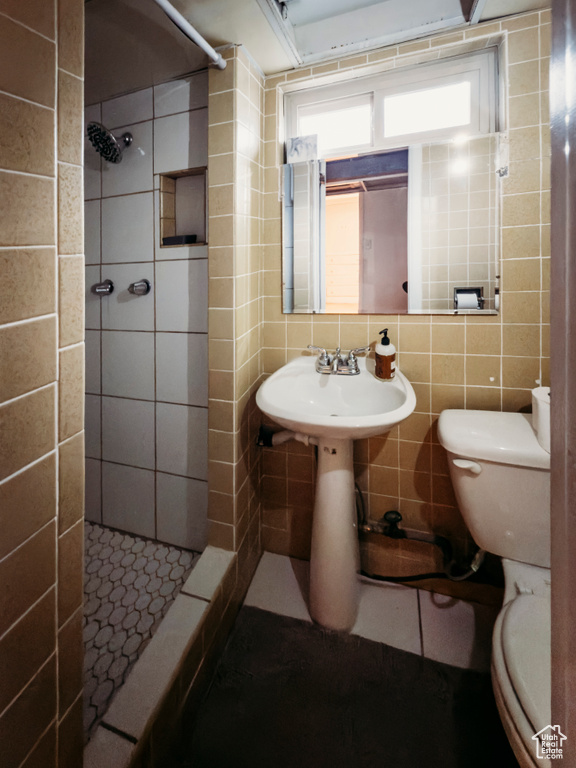 Bathroom featuring a shower stall, tile walls, toilet, tile patterned floors, and tasteful backsplash