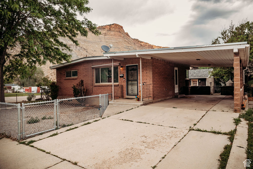 View of front of home with concrete driveway, a carport, a gate, and a mountain view