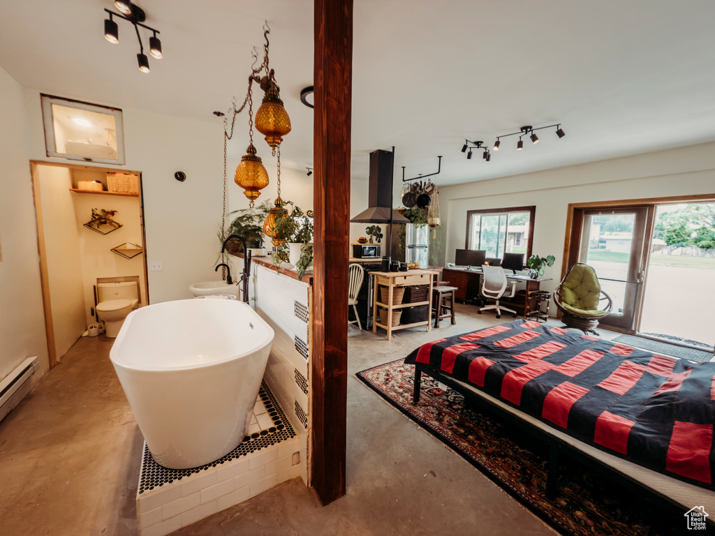 Bedroom featuring finished concrete floors, track lighting, access to exterior, and a baseboard heating unit