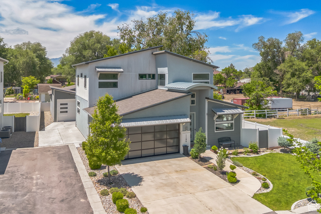 View of front of house featuring concrete driveway, stucco siding, metal roof, a standing seam roof, and a garage