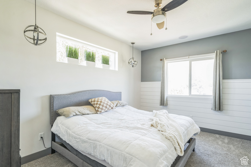 Bedroom with carpet floors, ceiling fan, and wooden walls