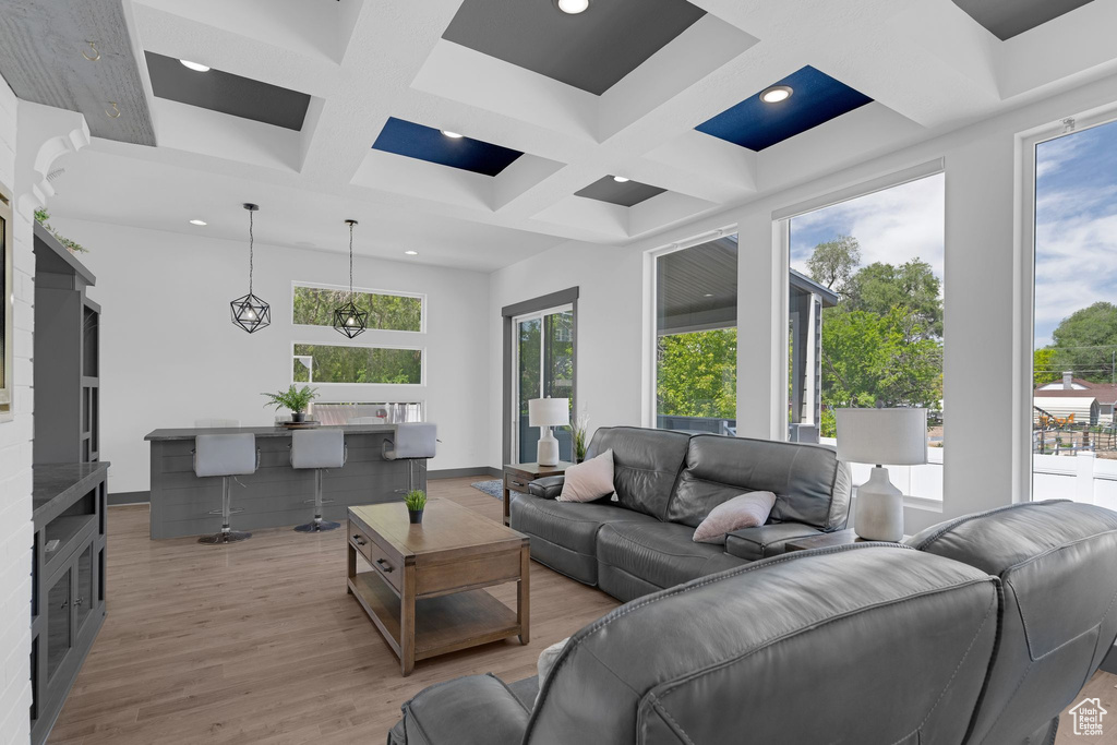 Living room with coffered ceiling, light wood finished floors, beamed ceiling, and recessed lighting