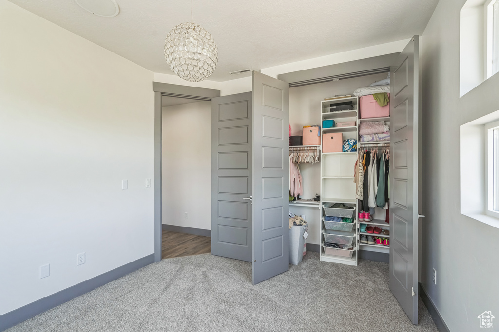 Carpeted bedroom with a closet, a chandelier, and baseboards