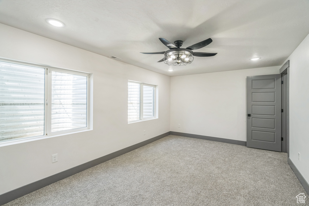 Spare room featuring light colored carpet, ceiling fan, recessed lighting, and baseboards