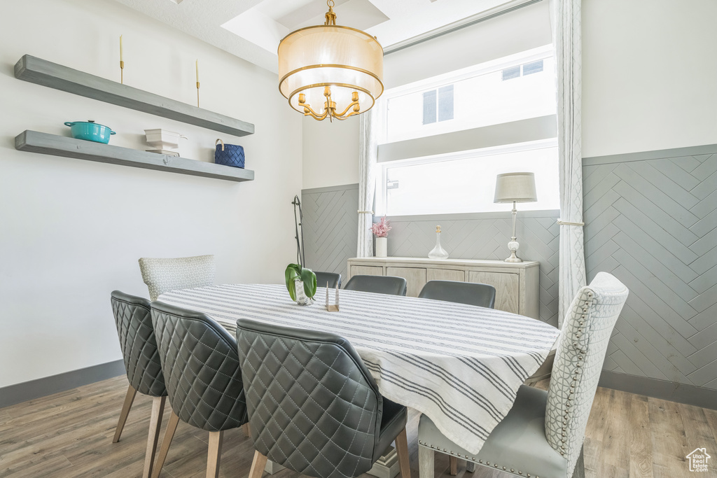 Dining space with a chandelier, wood finished floors, and wainscoting