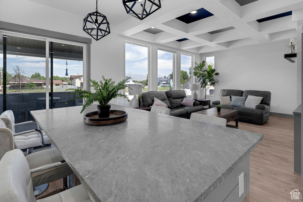 Dining room with light wood-style floors, coffered ceiling, and beamed ceiling