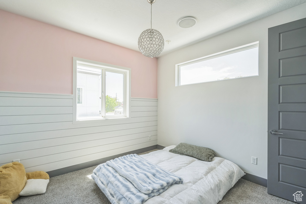 Bedroom with wooden walls, carpet flooring, and a wainscoted wall