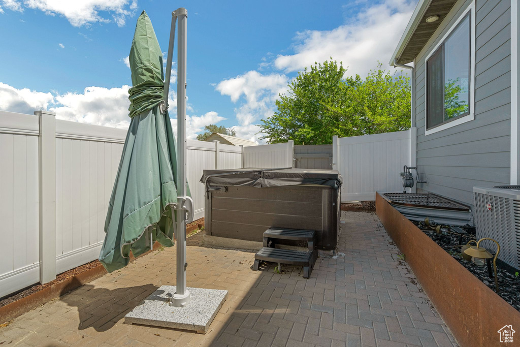 Fenced backyard with a hot tub, a patio, and central AC