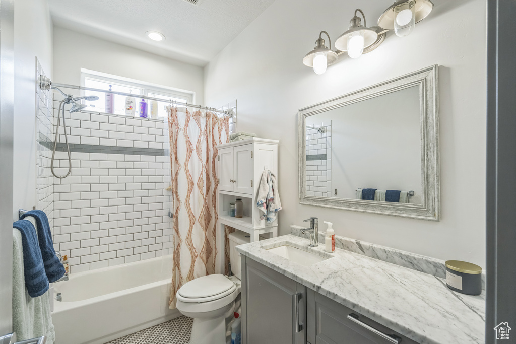 Full bathroom with vanity, shower / bath combo, and toilet