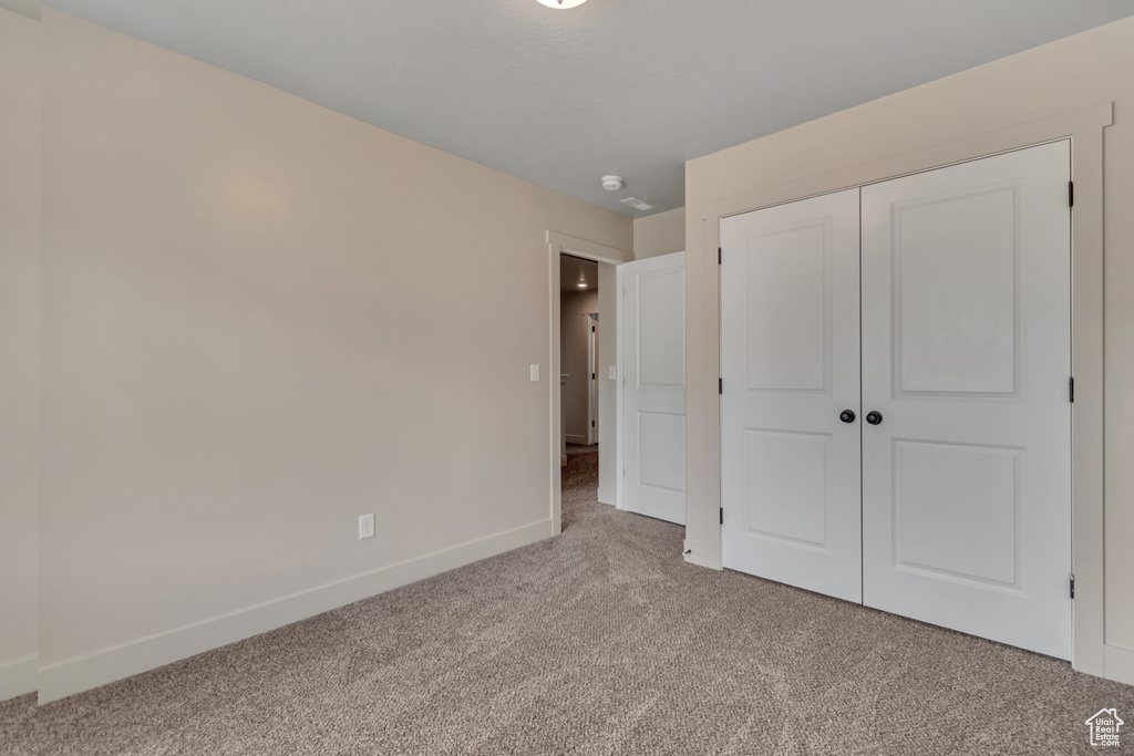 Unfurnished bedroom featuring carpet, baseboards, and a closet