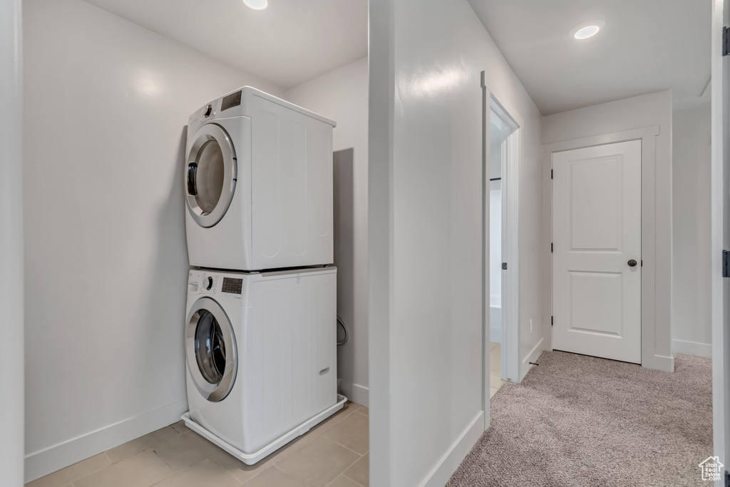 Laundry room with stacked washing machine and dryer, baseboards, and recessed lighting