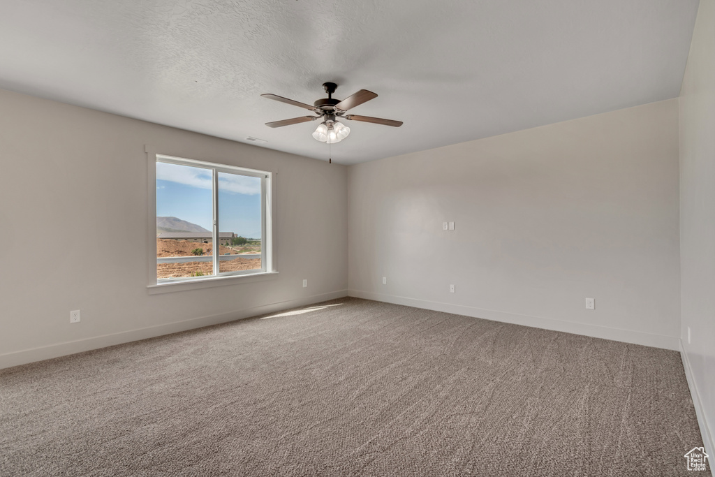 Unfurnished room with baseboards, a ceiling fan, and carpet