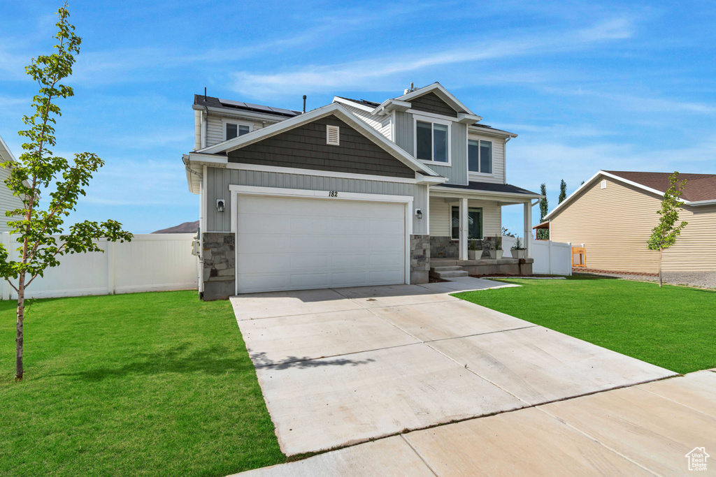 View of front of house featuring stone siding, covered porch, driveway, and a garage
