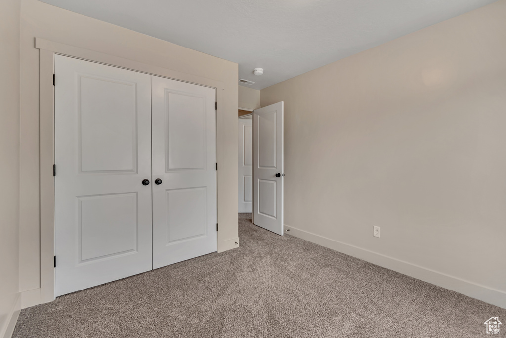 Unfurnished bedroom featuring carpet floors, a closet, and baseboards