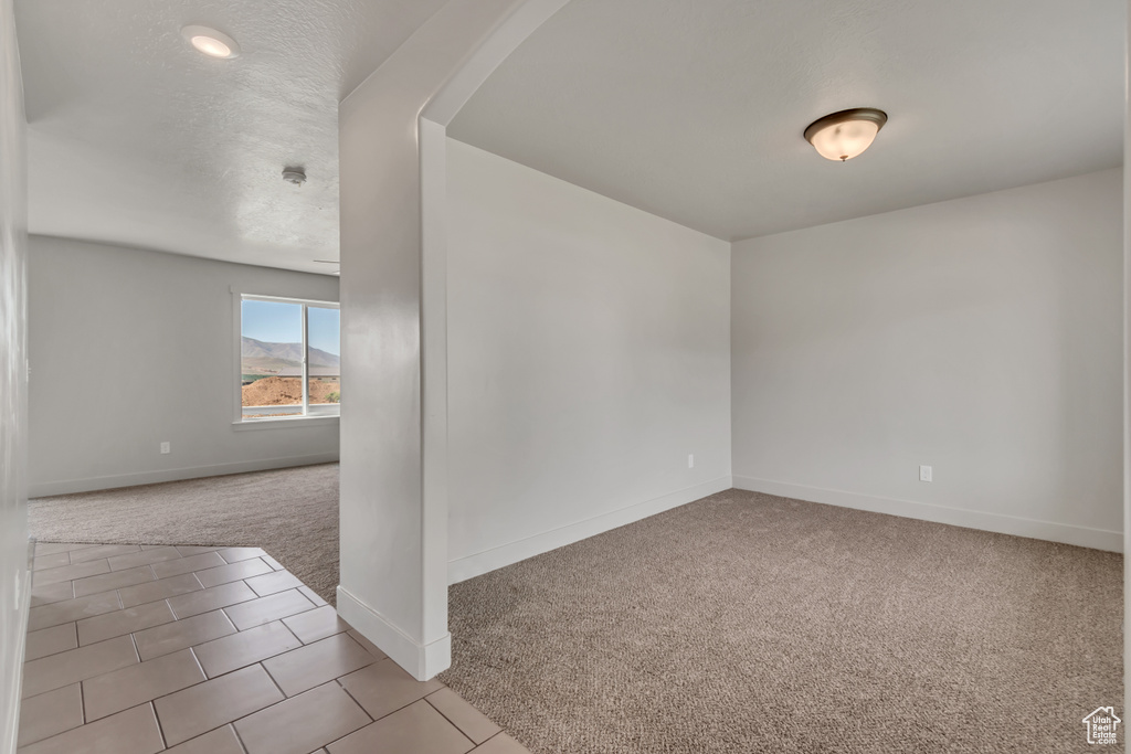 Unfurnished room with carpet floors, baseboards, and arched walkways