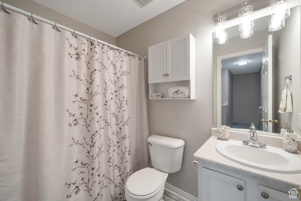 Bathroom with toilet, vanity, a shower with curtain, and baseboards