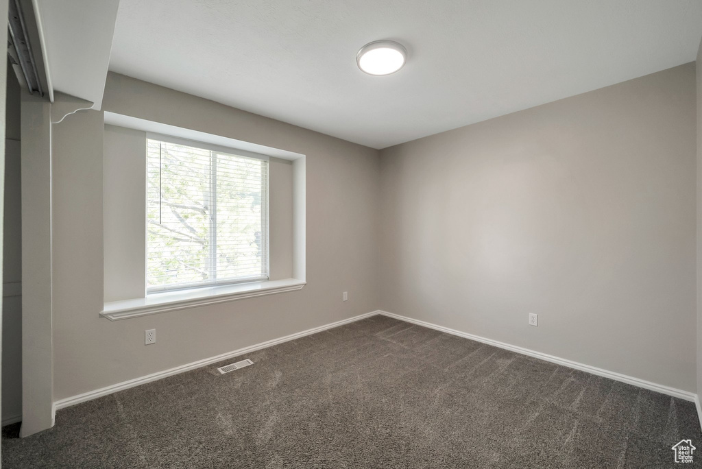 Unfurnished room featuring dark carpet and baseboards