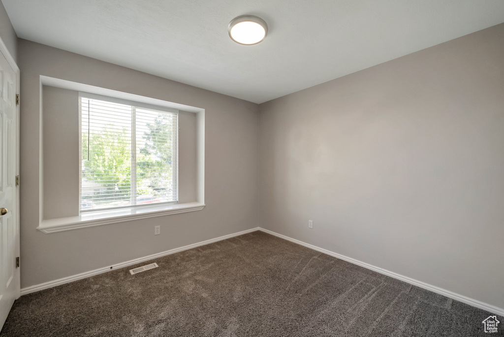 Unfurnished room featuring dark colored carpet and baseboards