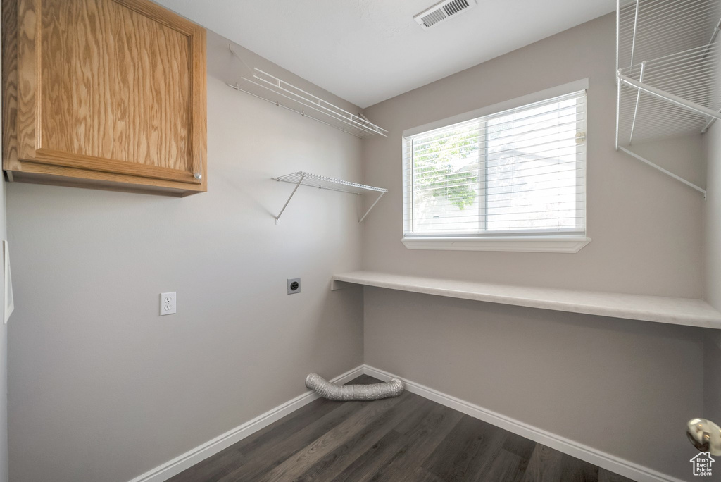 Washroom with baseboards, hookup for an electric dryer, dark wood finished floors, and cabinet space