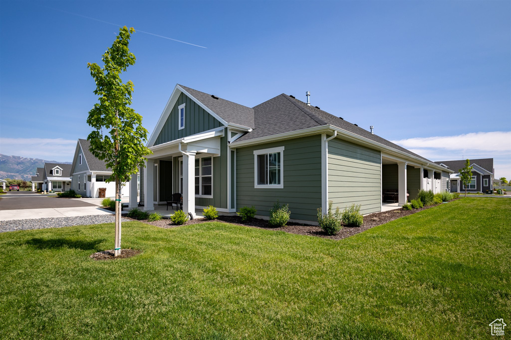 View of front of home featuring a front yard, board and batten siding, concrete driveway, and roof with shingles