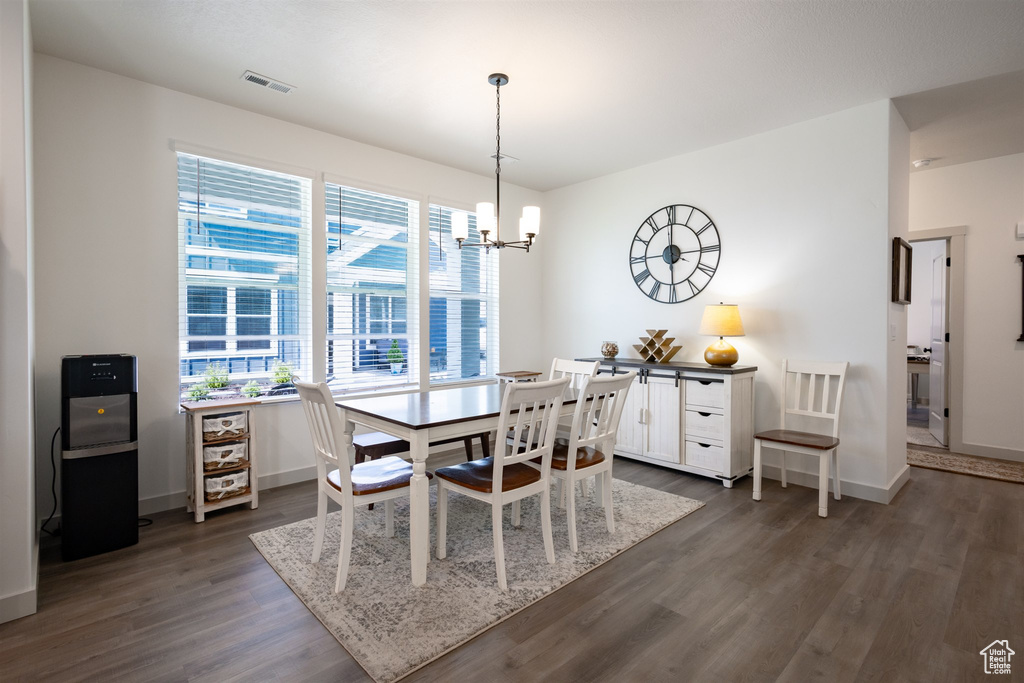 Dining space featuring dark wood-style flooring, a chandelier, and baseboards