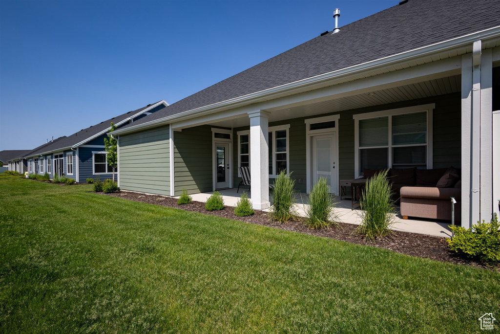 Rear view of house featuring a lawn, a shingled roof, and covered porch