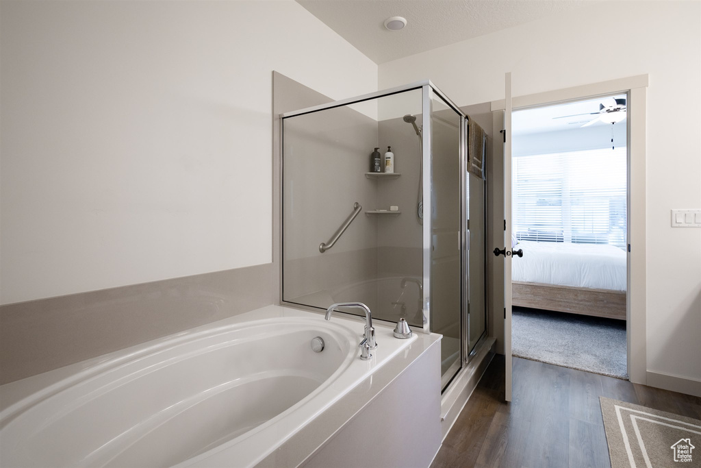 Ensuite bathroom featuring a garden tub, a shower stall, and wood finished floors